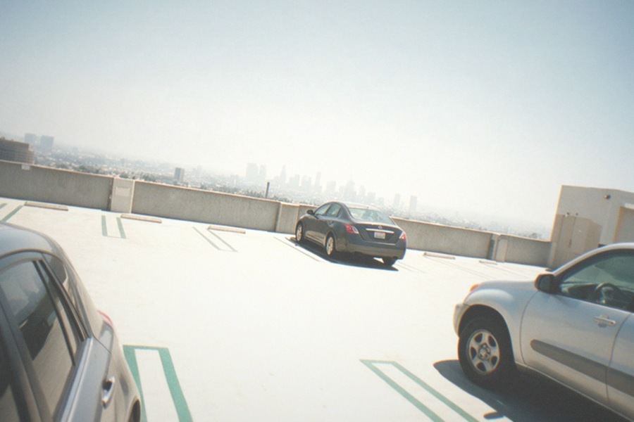 A wide sidewalk along a boulevard with museums on one side and parked cars along the curb
