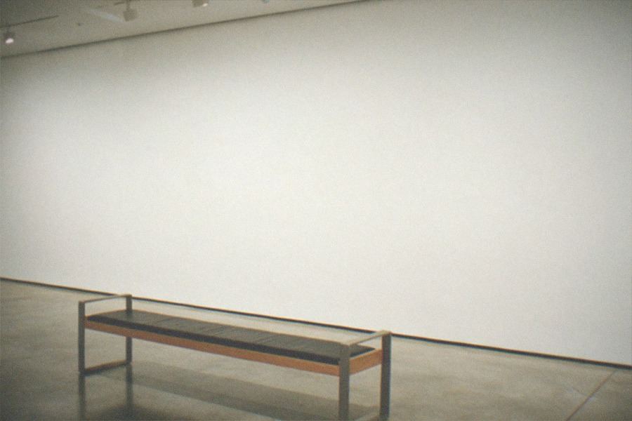 Visitors walking between classic cars in a wide museum gallery with polished floors