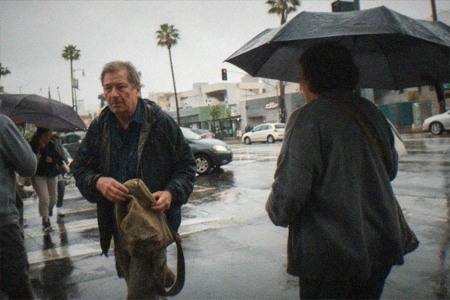 Rainy city street with headlights and reflections on wet pavement