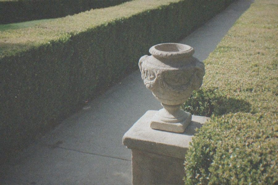 Formal botanical garden with manicured hedges and a museum building in the distance