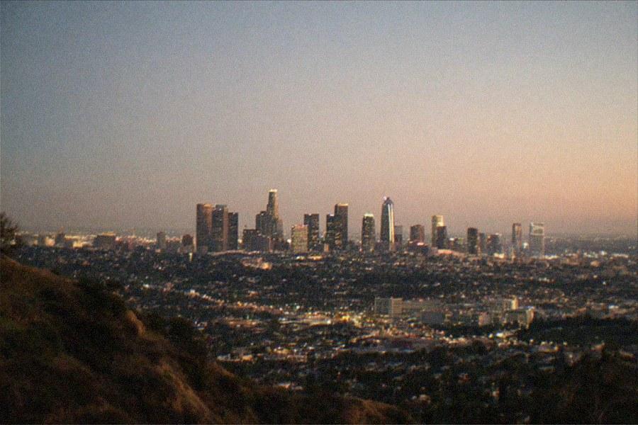 Hilltop observatory building with white domes seen from a park road at dusk